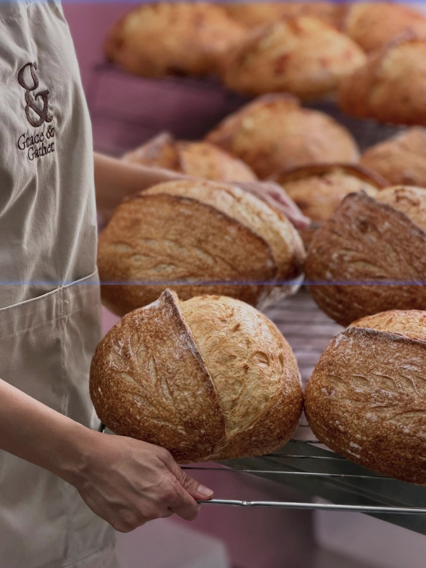 Artisan baker with freshly baked sourdough boules and leaf scoring on cooling racks